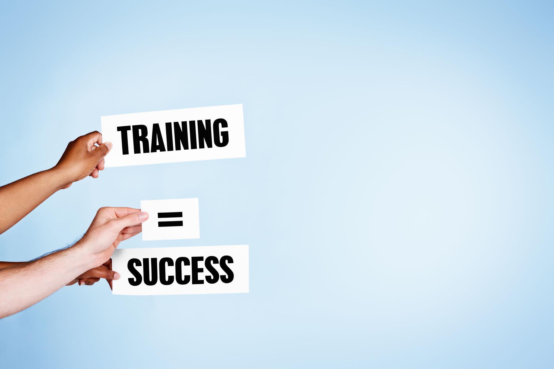 "Training = Success" say hand-held signs on sky-blue background